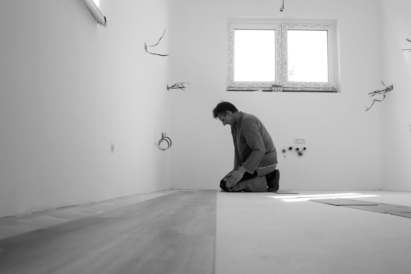 Person verlegt neuen Laminatboden in einem leeren Raum