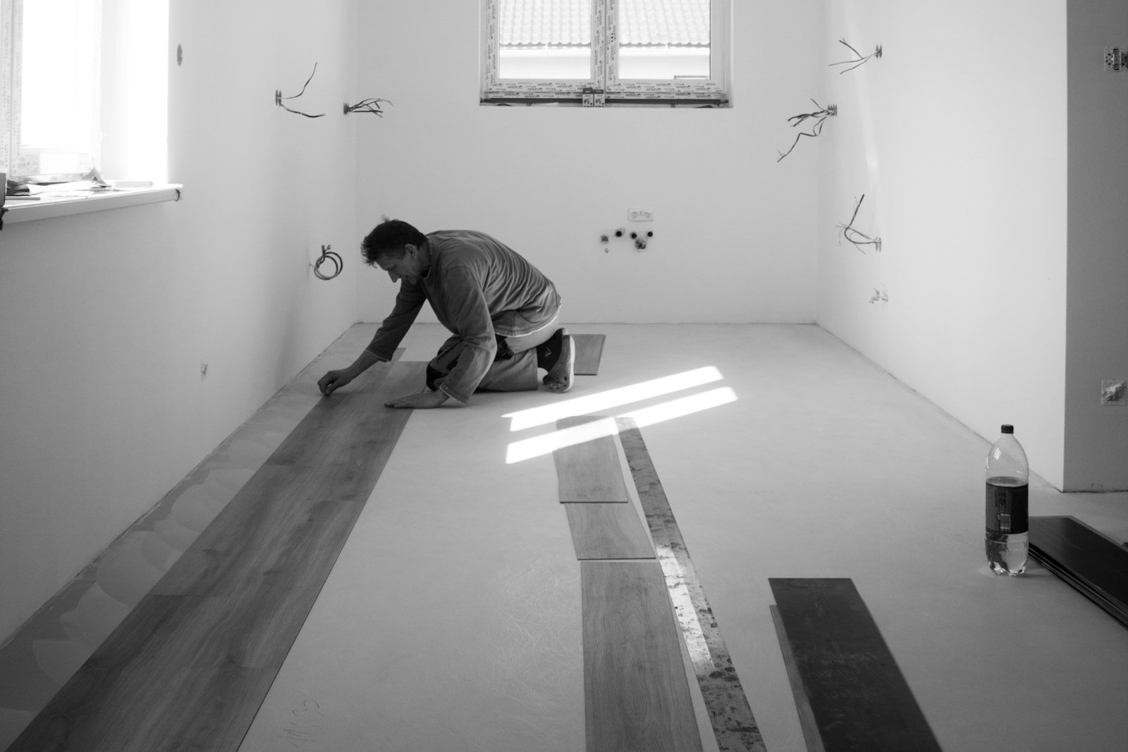 Person verlegt Laminatboden im Raum mit sichtbaren Dielen